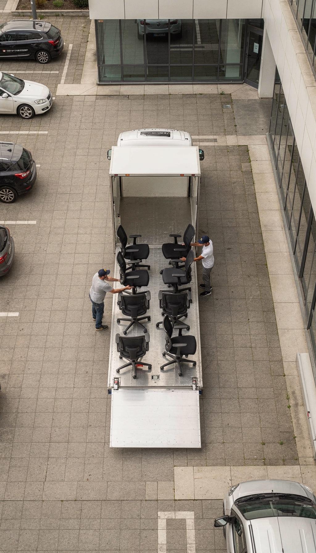 Luftaufnahme: Fenyx-Team verlädt Bürostühle in einen LKW vor einem Bürogebäude.