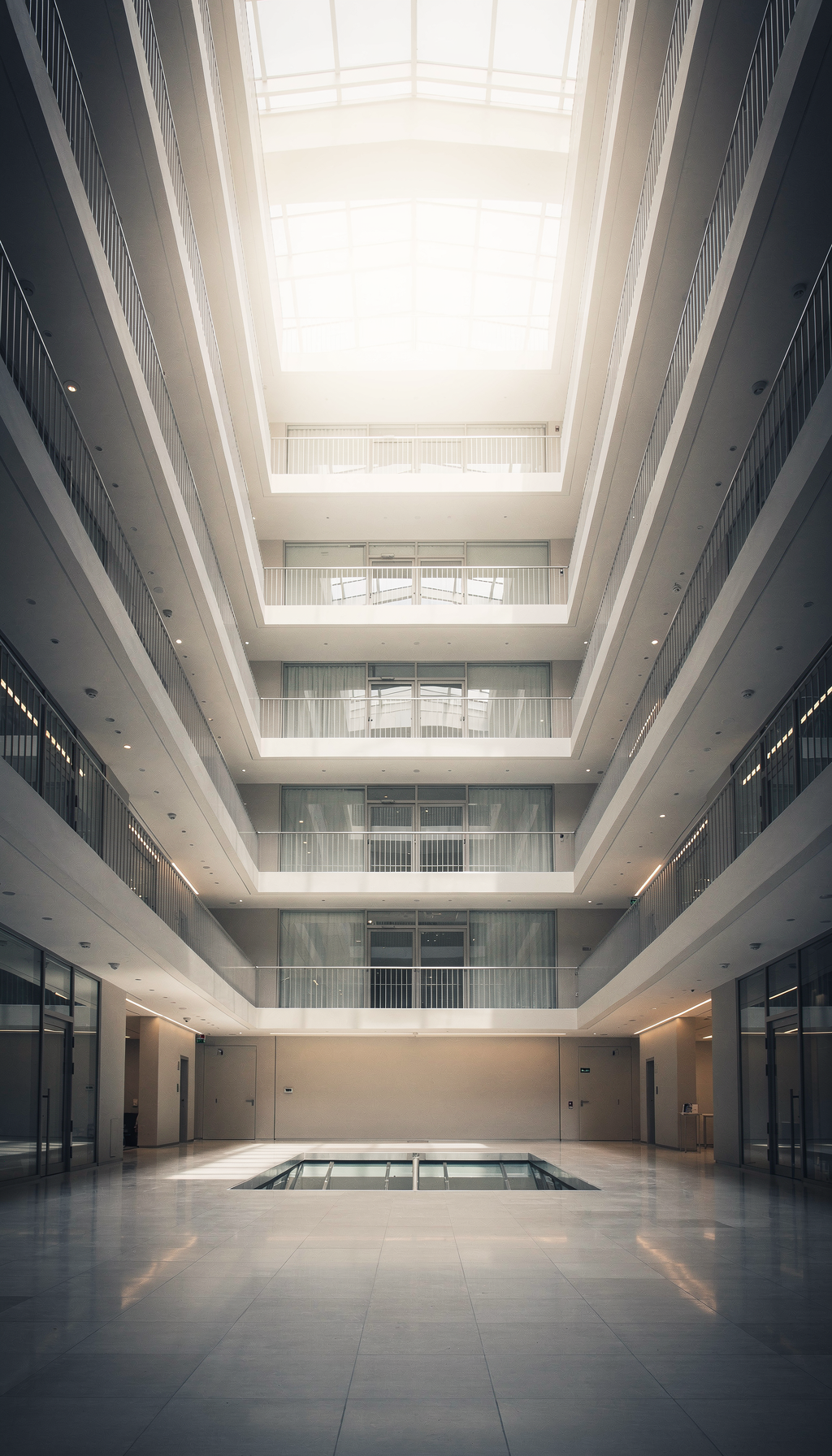 Blick nach oben in ein modernes Büroatrium mit Glasfassade und Galerien.