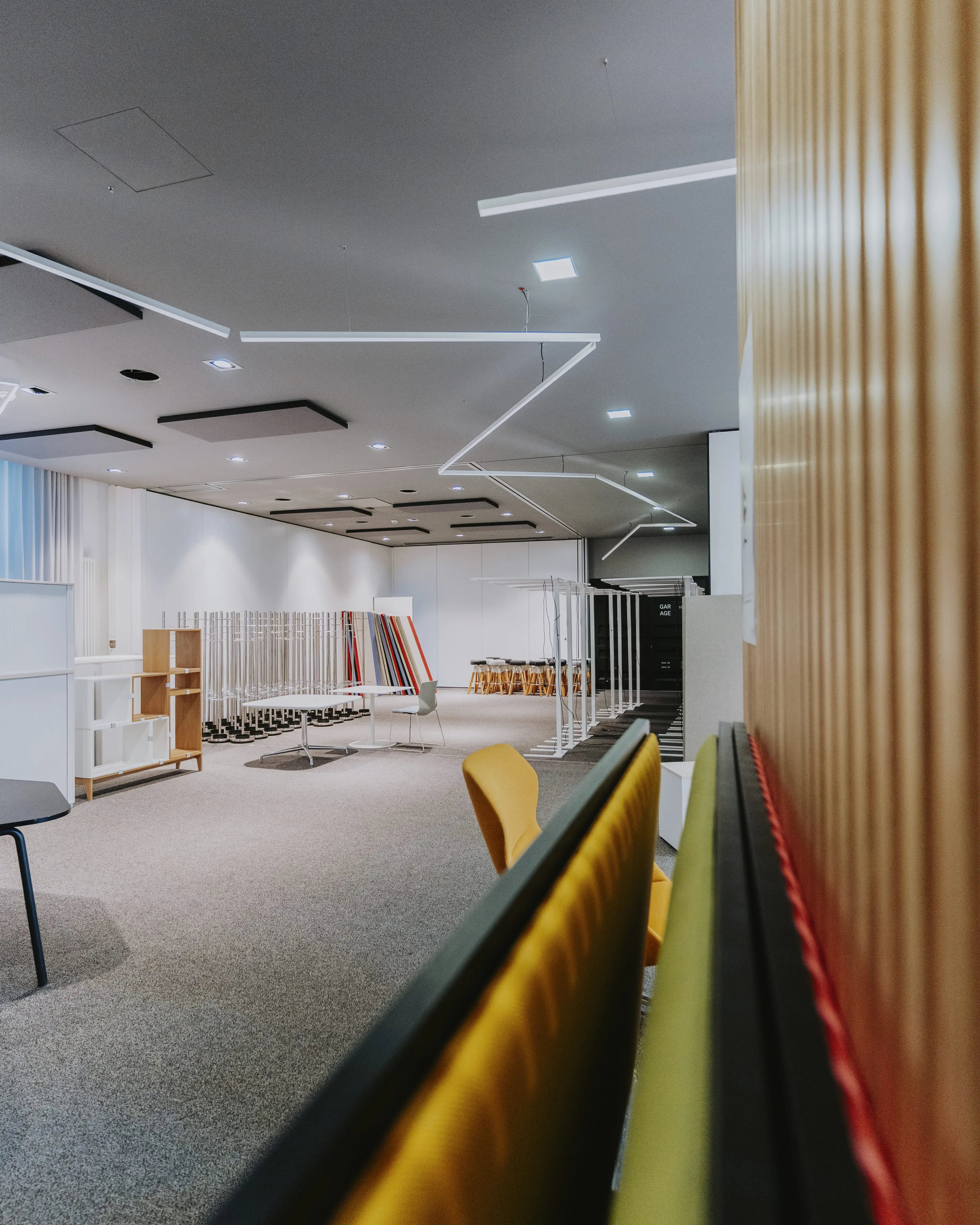 Büro im Umbau mit freiliegenden Decken, Holzlamellenwand, gelbem Absperrband und Baumaterialien auf dem Boden.